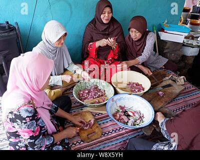 A group of muslim women (muslimah) prepare raw mutton satay and ingredients together. Stock Photo