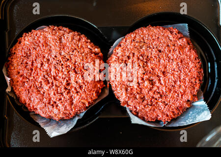 Flat top closeup of two raw uncooked red vegan plant based meat burger patties in packaging Stock Photo