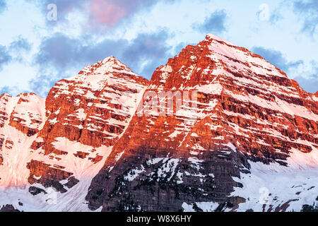 Maroon Bells red sunrise light peak closeup in Aspen, Colorado during blue hour cloudy sky and snow in early summer Stock Photo