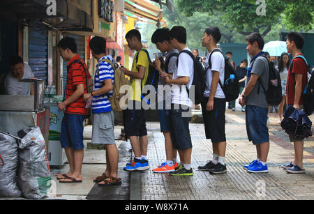 Customers queue up outside the food stall of the meat pie hawker Shao Jianhua, left, who resembles Chinese President Xi Jinping, in Changsha city, cen Stock Photo