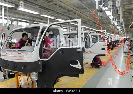 --FILE--Chinese workers assemble trucks on the assembly line at the auto plant of Anhui Jianghuai Automobile Co., Ltd. (JAC) in Qingzhou city, east Ch Stock Photo