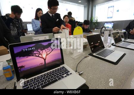--FILE--Chinese customers try out or buy MacBook laptop computers at an authorized store of Apple in Xuchang city, central Chinas Henan province, 12 J Stock Photo