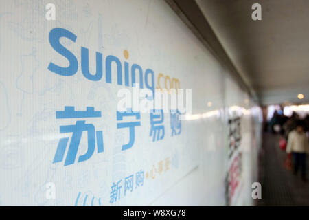 --FILE--Pedestrians walk past an advertisement for online shopping website Suning.com of Suning Group in Shanghai, China, 14 January 2014.   Suning Co Stock Photo