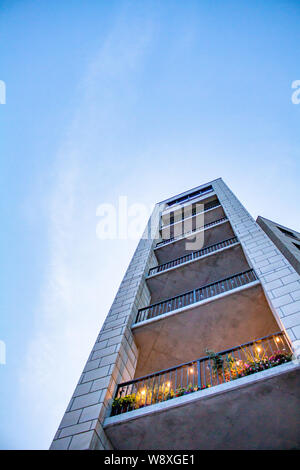 Looking up at a tower of condo balconies from street level in the early evening. Stock Photo