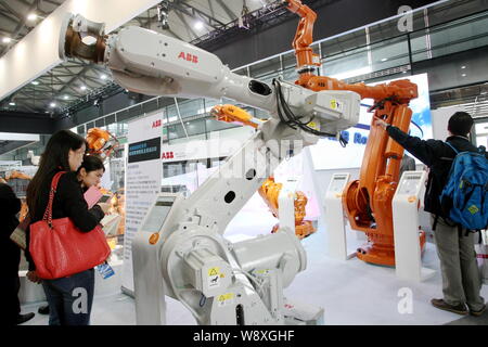 --FILE--Visitors look at robot arms of ABB at the 15th China International Industry Fair in Shanghai, China, 7 November 2013.   ABB, a leading power a Stock Photo