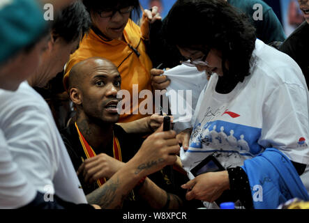 American basketball player Stephon Marbury of Chinas Beijing Ducks, center, prepares to sign on the T-shirt of a Chinese fan at a celebration party fo Stock Photo