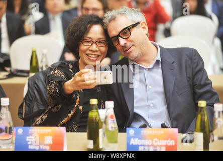 Mexican film director Alfonso Cuaron, right, poses for photos with Chinese director Ning Ying during the Sino-Foreign Film Co-production Forum of the Stock Photo