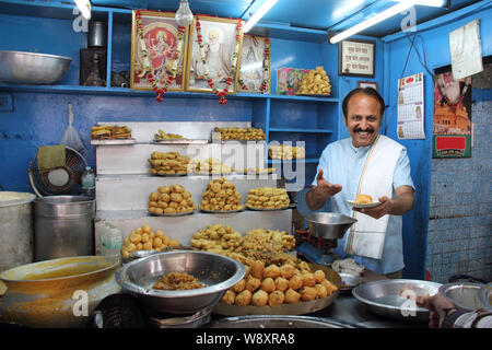 Shopkeeper giving a plate of pakora to a customer Stock Photo