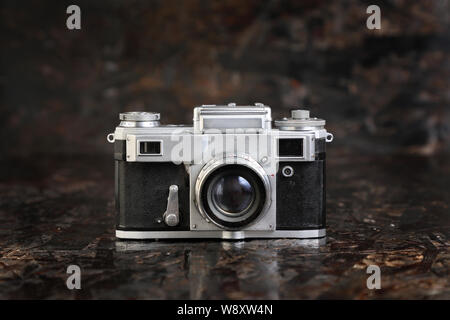 Old vintage film camera on brown dark texture background . Stock Photo