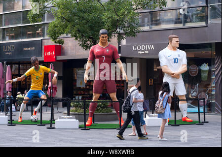 Visitors walk past three giant figures of football superstars (from left) Neymar of Brazil, Cristiano Ronaldo of Portugal and Wayne Rooney of England Stock Photo