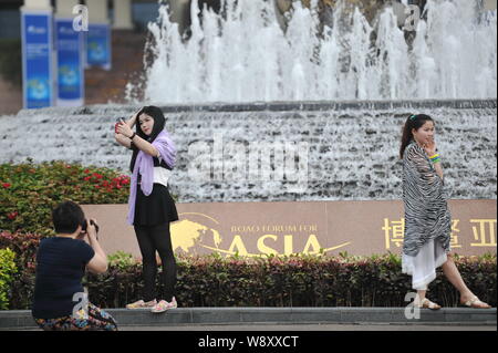 People take photos in front of the fountain at the BFA International Convention Center ahead of the Boao Forum for Asia Annual Conference 2014 in Qion Stock Photo