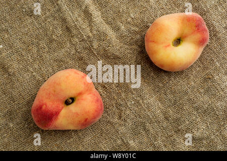Donut Peaches also known as Saturn peaches on a rustic canvas background. Healthy food consept. Stock Photo