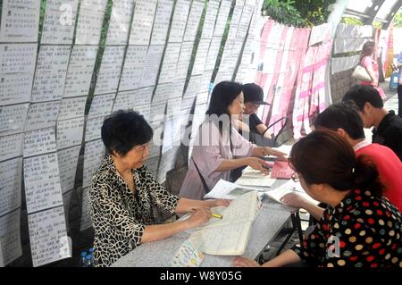 --FILE--Marriage agents talk to parents in front of pieces of contact information hanging on trees at the Matchmaking Corner in the Peoples Park in Sh Stock Photo