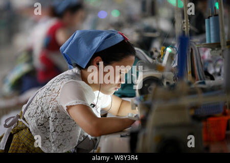 A female Chinese worker sews clothes at a garment factory in Huaibei city,  east China's Anhui province, 20 January 2015. China's working-age populat  Stock Photo - Alamy