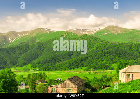 Mountain peaks covered with snow and green meadows on a sunny day in Armenia Stock Photo