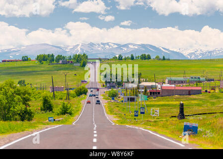 motorway through the village of Armenia overlooking the mountains with snowy peaks Stock Photo