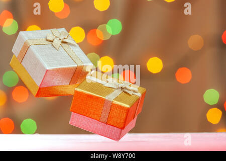 Two gift boxes gold and silver with a bow on a blurry color with lights bokeh background with place for text. Stock Photo