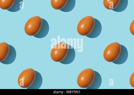 Brown eggs pattern on blue background. Creative layout. Top view. Stock Photo