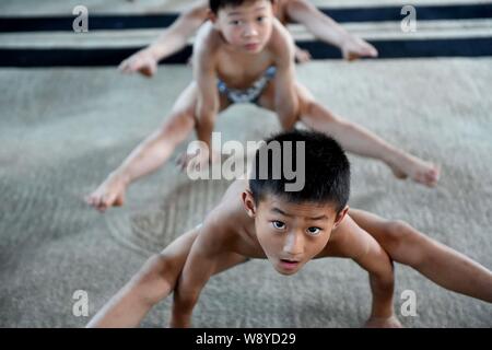 Young Chinese boys bend their bodies to keep balance with their hands on the floor to practice gymnastics at a gymnastics training center in Bozhou ci Stock Photo