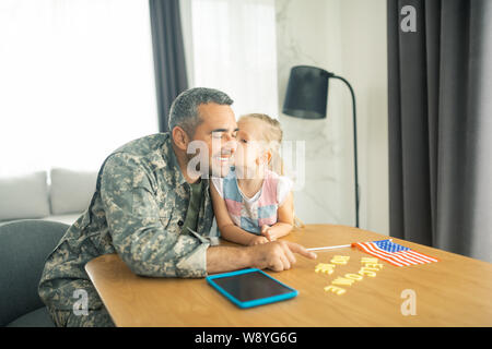 Daughter kissing father coming home after military service Stock Photo
