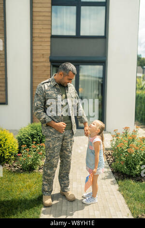 Little daughter standing near her American hero coming back home Stock Photo