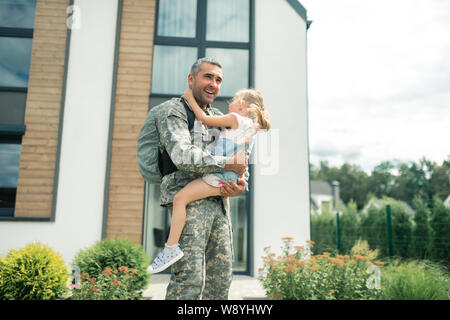 Serviceman feeling amazing standing near house with daughter Stock Photo