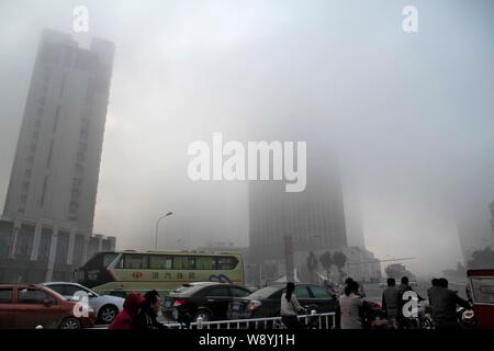 High-rise buildings are seen vaguely in heavy smog in HuaiAn city, east Chinas Jiangsu province, 29 September 2013. Stock Photo