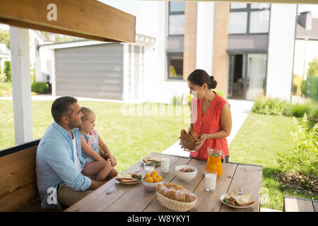 Mother bringing bowl with cookies while having breakfast outside Stock Photo