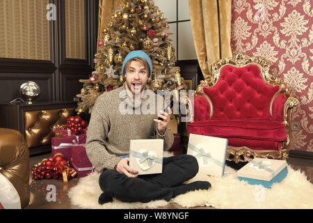 Man with surprised face open gift box at christmas tree. Boxing day ...
