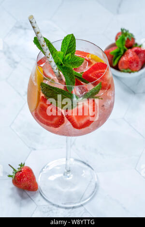 Pink gin and tonic cocktail with prosecco and strawberries, garnished with fresh mint - refreshing summer alcoholic drink Stock Photo