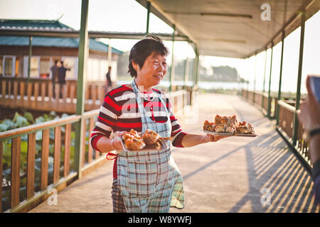 A waitress serves customers with steamed hairy crabs at a restaurant on the bank of the Yangcheng Lake in Kunshan, Suzhou city, east China's Jiangsu p Stock Photo