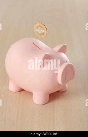 Ten rupee coin is being falling into a piggy bank Stock Photo