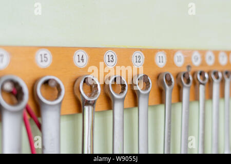 collection of spanners hanging on the wall on a wooden holder Stock Photo