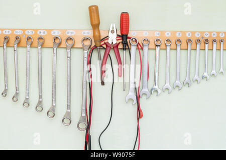 collection of spanners hanging on the wall on a wooden holder Stock Photo