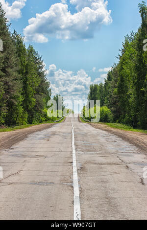 highway into the horizon with a bright white dividing strip, old broken rough country road, vertical Stock Photo