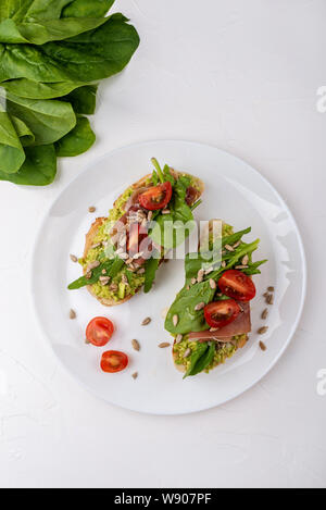 Sandwiches with avocado cream, tomatoes and jamon. Stock Photo