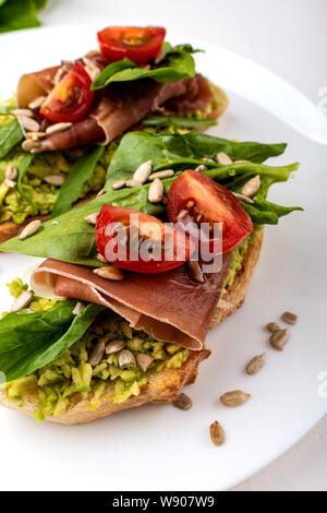 Sandwiches with avocado cream, tomatoes and jamon. Stock Photo