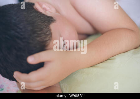 sleeping little caucasian boy with closed eyes lying on green pillow during deep sleep in morning Stock Photo