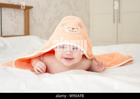 cheerful baby boy girl looks out from under the towel, laughing face of a child, happy childhood. Caucasian child 6 months old portrait looking into c Stock Photo