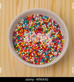 Multicolored sweet pea balls for decorating culinary products baking cakes. Dessert decoration, colored sprinkles for Easter cakes in a white bowl, sq Stock Photo