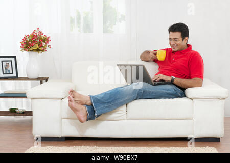 Senior man working on laptop and having a cup of coffee Stock Photo