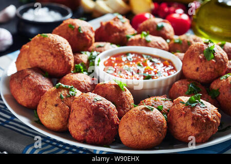 close-up of deep fried Plantain fritters Klako on a white plate with hot pepper and tomato sauce, african cuisine, horizontal view Stock Photo
