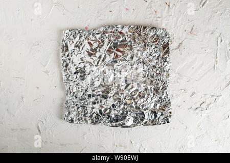 a piece of crumpled foil on color surface Stock Photo
