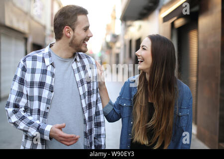 Front view portrait of a happy friends flirting walking towards you in the street Stock Photo