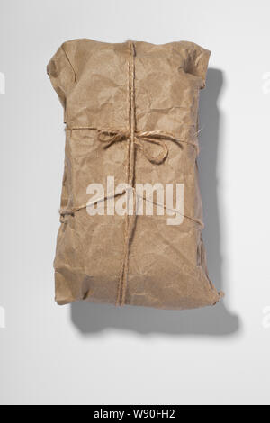 old tied up parcel on a white background Stock Photo - Alamy