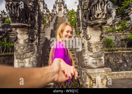 follow me photo. Young woman tourist on background of Three stone ladders in beautiful Pura Lempuyang Luhur temple. Summer landscape with stairs to Stock Photo