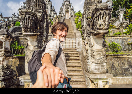 follow me photo. Young man tourist on background of Three stone ladders in beautiful Pura Lempuyang Luhur temple. Summer landscape with stairs to Stock Photo