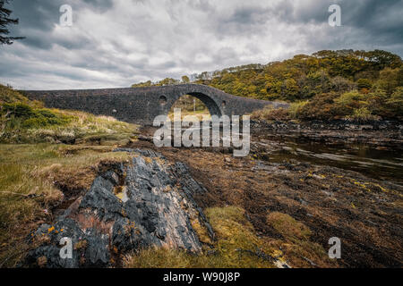 Clachan Bridge, a stone, single arch bridge, built in 1793 and known as the Bridge over the Atlantic, spans Clachan Sound between mainland Scotland an Stock Photo