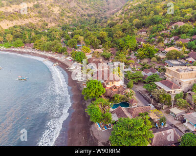 Aerial view of Amed beach in Bali, Indonesia. Traditional fishing boats called jukung on the black sand beach and Mount Agung volcano in the