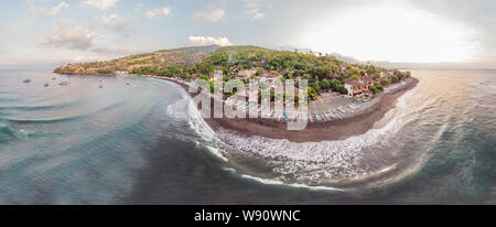 Aerial view of Amed beach in Bali, Indonesia. Traditional fishing boats called jukung on the black sand beach and Mount Agung volcano in the Stock Photo